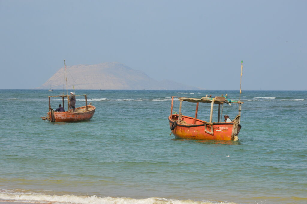 Two fishing boats sit offshore with Charna Island on the horizon