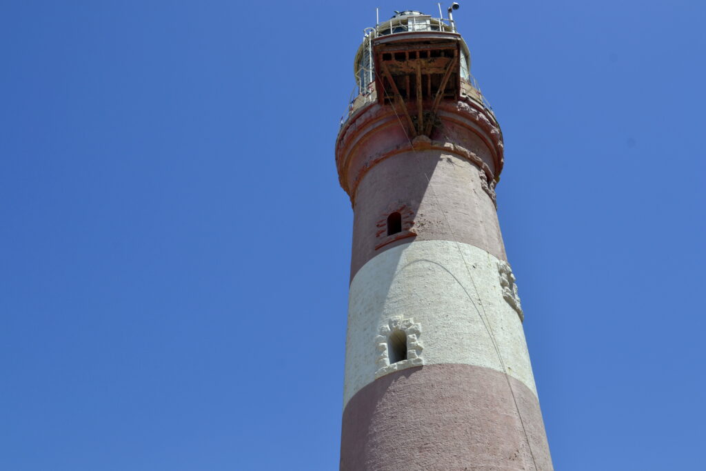 The banded tower of Manora Point Lighthouse rises against a clear sky