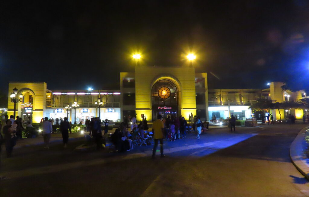Visitors gather in the forecourt of the arched Port Grand entrance at night